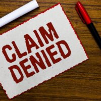 Handwriting text writing Claim Denied. Concept meaning Requested reimbursement payment for bill has been refused White paper red borders markers wooden background communicating ideas.