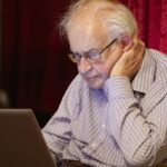 Old elderly senior person learning computer and online internet skills to prevent fraud