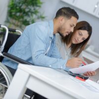 couple at home reading document, man in wheelchair