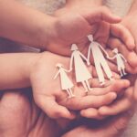 Adult and children hands holding paper family cutout, family hom Adult and children hands holding paper family cutout, family hom