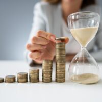 Businesswoman With Hourglass And Stack Of Coins Businesswoman With Hourglass And Stack Of Coins