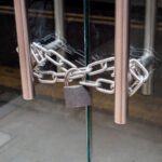 A retail shop glass front doors, padlocked and chained shut. For