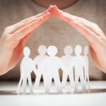 Paper people under hands in gesture of protection. Concept of insurance, social protection and support. Paper people under hands in gesture of protection. Concept of insurance, social protection and support.